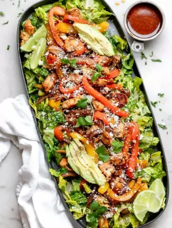 chicken fajita salad on a platter with extra dressing on the side
