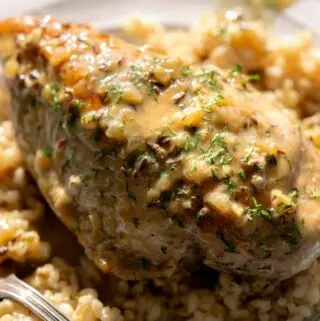 dill chicken recipe on a plate over rice with herbs