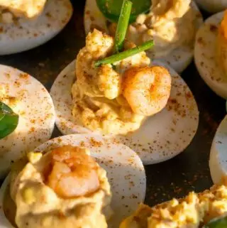 cajun shrimp deviled eggs on a platter with chives and jalapenos
