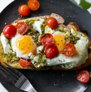 pesto eggs recipe with tomatoes on top, over a toasted piece of bread