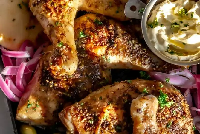 za'atar chicken recipe on a baking sheet with onions and olives