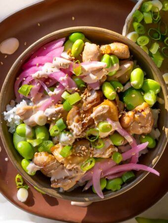 chicken poke bowl recipe with edamame, sauce, and pickled onions in a bowl